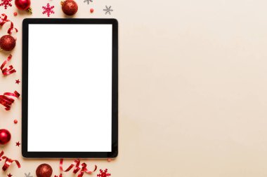 Noel alışverişi boş beyaz ekranlı tablet bilgisayardan yapılıyor. Renkli arka planda noel süsleme toplarıyla fotokopi alanı olan tablet. Kış tatillerinde satış geçmişi.