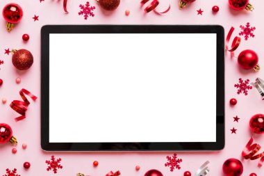 Noel alışverişi boş beyaz ekranlı tablet bilgisayardan yapılıyor. Renkli arka planda noel süsleme toplarıyla fotokopi alanı olan tablet. Kış tatillerinde satış geçmişi.