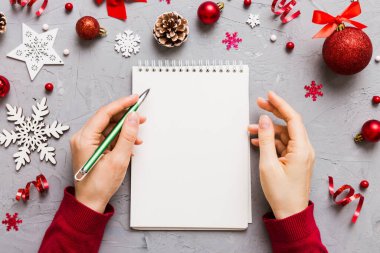 Noel 'i yazmak için bir kadın not defterine Xmas dekorasyonlu renkli arkaplan çiziyor.