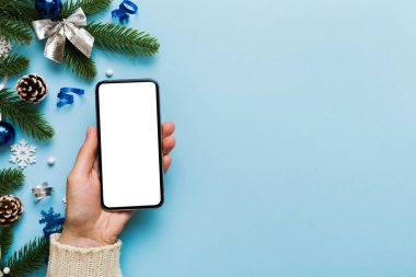 Mesaj atmak için yeri olan bir Noel modeli. Noel reklamı, uygulama şablonu. Masa arkasında boş ekran olan el ele tutuşan telefon. Mutlu yıllar ve Xmas Flat.