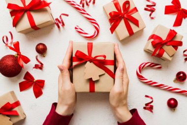 Kadınlar Noel tatili için sürpriz hediyeler hazırlıyor. İş yerinde el aletleri ve manzarayla oturuyor. Renkli masada Noel hediyesini paketleyen kadın..