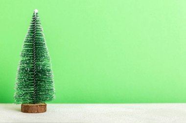One small Christmas tree on colored background. new year decoration with copy space.