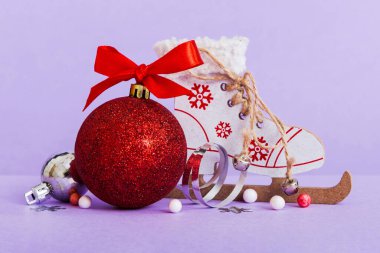 Christmas ball with skates on colored background. decoration bauble with ribbon bow with copy space.