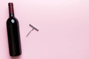 Renkli masada tirbuşonlu bir şişe kırmızı şarap. Düz konum, üst görünüm kopyalama alanı.