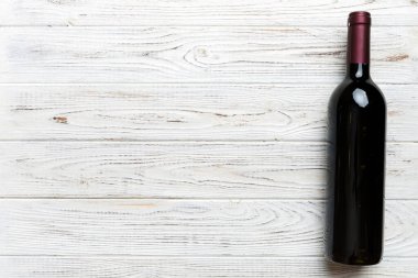 Renkli masada bir şişe kırmızı şarap. Düz konum, üst görünüm kopyalama alanı.