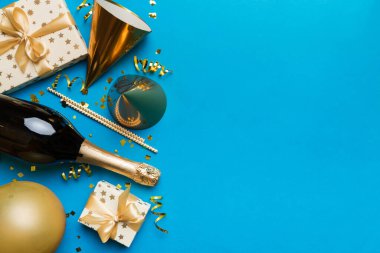 Renkli arka planda şampanya şişesi hediye paketi kurdeleleri ve konfetilerin düz kompozisyonu vardı. Düz konum, üst görünüm tatil konsepti.