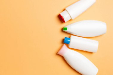 Renkli arkaplanda izole edilmiş Beyaz Kozmetik konteynırları seti, fotokopi alanı ile üst görünüm. Senin için bir grup plastik kaplar ve boş bir yer tasarladın..