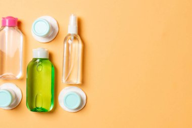 Renkli arka planda seyahat etmek için bir grup küçük şişe. Fikirlerin için uzayı kopyala. Kozmetik ürünlerin düz bileşimi. Pamuklu krema kaplarının üst görüntüsü.