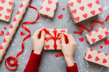 Women hands pack gifts and make decorations for the holiday, top view. Birthday and valentine present.