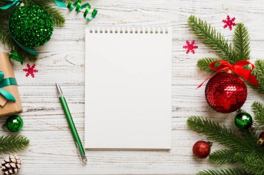 Noel 'i yazmak için bir kadın not defterine Xmas dekorasyonlu renkli arkaplan çiziyor.