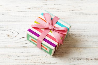 Noel 'i ya da diğer tatil hediyelerini renkli arka planda kurdeleyle renkli kağıda sardım. Şimdiki kutu, renkli tabloda hediye süslemesi, kopya alanı ile üst görünüm.