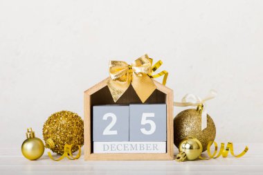 25 december. Christmas composition on colored background with a wooden calendar, with a gift box, toys, bauble copy space.