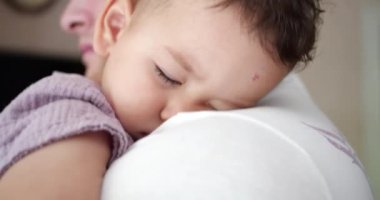 Küçük bir bebek babasının kollarında uyuyakaldı. Babam evde uyumak için bebeği sallıyor. yakın plan.