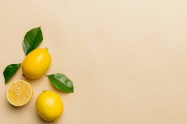 Renkli arka planda yeşil yapraklı taze limonlar, üst görünüm, metin için boşluk.