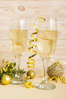 Champagne glasses and christmas decor on colored holiday background. Flat lay New Year decorations.