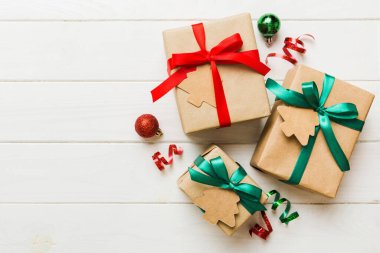 wrapped christmas or other holiday handmade present in paper with colored ribbon. Present box, decoration of gift on colourfull table, top view with copy space.