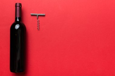 Renkli masada tirbuşonlu bir şişe kırmızı şarap. Düz konum, üst görünüm kopyalama alanı.