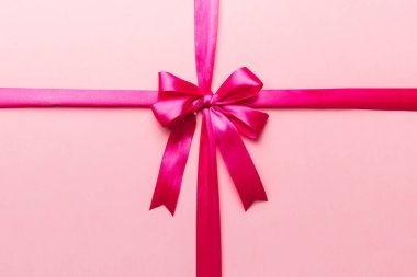 Mor kurdelenin üst görüntüsü yuvarlandı ve pembe fiyonk renkli arka planda izole edildi. Kopyalama alanı olan düz.