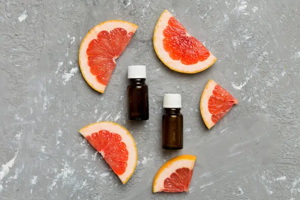 Bottles with Grapefruit fruit essential oil on wooden background. alternative medicine top view with copy space.