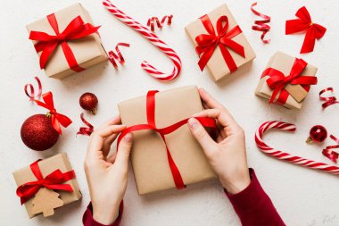 Kadınlar Noel tatili için sürpriz hediyeler hazırlıyor. İş yerinde el aletleri ve manzarayla oturuyor. Renkli masada Noel hediyesini paketleyen kadın..