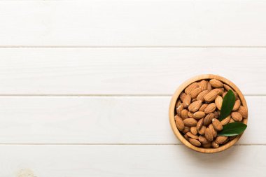 Fresh healthy Almond in bowl on colored table background. Top view.