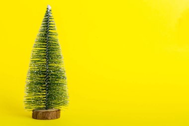 One small Christmas tree on colored background. new year decoration with copy space.