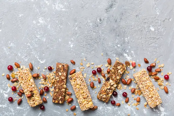 Various granola bars on table background. Cereal granola bars. Superfood breakfast bars with oats, nuts and berries, close up. Superfood concept.