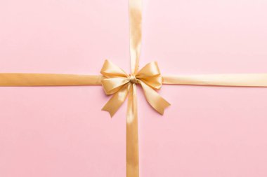 Altın kurdelenin üst görüntüsü yuvarlandı ve sarı fiyonk renkli arka planda izole edildi. Kopyalama alanı olan düz.