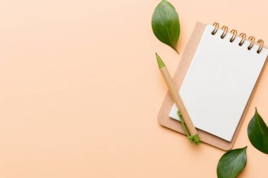 Not için Renkli arkaplan üzerinde kalem ve yeşil yaprak ile çevre dostu boş not defteri.