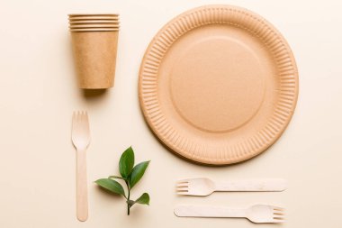Açık beyaz masa arkaplanındaki boş, tek kullanımlık çevre dostu tabaklar, bardaklar, çatal bıçaklar. Üst Manzara. Biyo-çözünebilir el yapımı yemekler. Geri dönüşüm konsepti. Yakın plan..