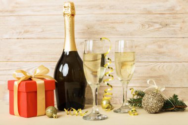 Champagne bottle with confetti, glasses and christmas decor on colored holiday background. Flat lay New Year decorations.