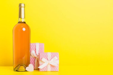 Bottle of wine on colored background for Valentine Day with gift box. Heart shaped with presrnt box perspective view with copy space.