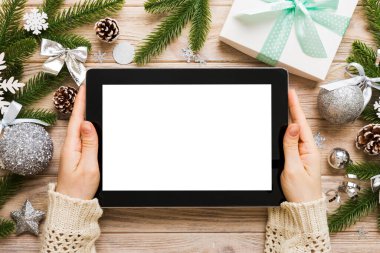 Evden Noel alışverişi, kadın elleri boş beyaz ekranlı tableti tutuyor. Kadın elinde tablet, boş ekran, Noel ağacı ve arka planda hediyeler..