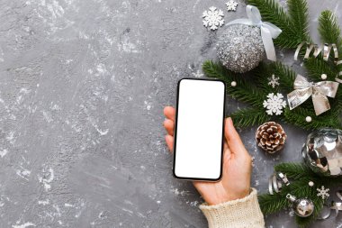 Mesaj atmak için yeri olan bir Noel modeli. Noel reklamı, uygulama şablonu. Masa arkasında boş ekran olan el ele tutuşan telefon. Mutlu yıllar ve Xmas Flat.