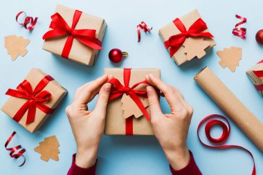 Kadınlar Noel tatili için sürpriz hediyeler hazırlıyor. İş yerinde el aletleri ve manzarayla oturuyor. Renkli masada Noel hediyesini paketleyen kadın..