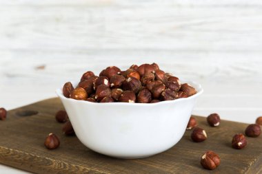 Wooden bowl full of hazelnuts on table background. Healthy eating concept. Super foods.