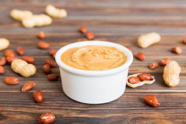 Arka planda bir kase fıstık ezmesi ve fıstık. Kopyalama alanı olan üst görünüm. Küçük kasede kremalı fıstıklı makarna.