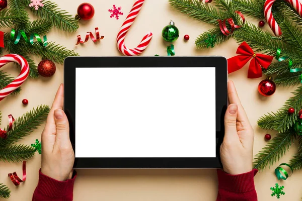 Evden Noel alışverişi, kadın elleri boş beyaz ekranlı tableti tutuyor. Kadın elinde tablet, boş ekran, Noel ağacı ve arka planda hediyeler..