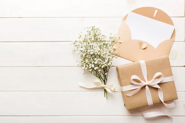 Wedding mockup with white paper list and flowers gypsophila on colored table top view flat lay. Blank greeting cards and envelopes. Beautiful floral pattern. Flat lay style.