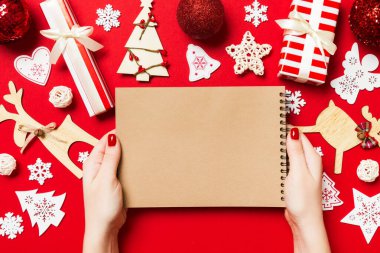 Kadın elinin rengarenk arka planda notlar aldığına dair üst görünüm. Yeni yıl süslemeleri ve oyuncakları. Noel zamanı konsepti.