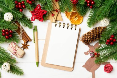 Köknar ağacı dalları, defter ve ahşap arka planda şenlikli dekoratif oyuncaklar. Yeni yıl konsepti.