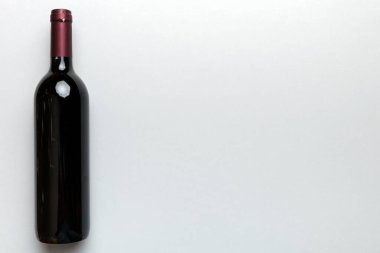 Renkli masada bir şişe kırmızı şarap. Düz konum, üst görünüm kopyalama alanı.
