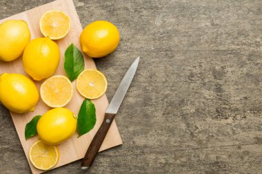 Kesme tahtasındaki taze ve olgun limonlar için fotokopi alanı olan üst manzara. Sağlıklı yemek geçmişi. Limon ve limon dilimlerinin, sıkacağı ve bıçak renginde arka planı çok zarif..