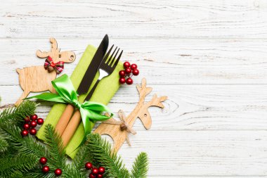 Tahta arka plandaki tatil eşyalarının üst görüntüsü. Utensiller peçeteye kurdele ile bağlanmış. Noel süsleri ve fotokopi alanı olan ren geyikleri. Yeni yıl yemeği konsepti.