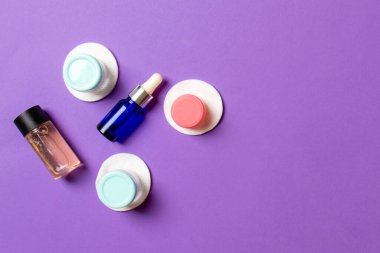 Renkli arka planda seyahat boyutunda kozmetik şişeler. Krema kavanozları düzdü. Vücut bakım stili kavramının en üst görünümü.