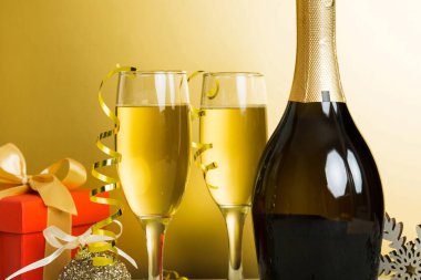 Champagne bottle with confetti, glasses and christmas decor on colored holiday background. Flat lay New Year decorations.
