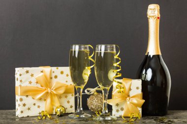 Champagne bottle with confetti, glasses and christmas decor on colored holiday background. Flat lay New Year decorations.