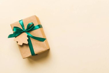 wrapped christmas or other holiday handmade present in paper with colored ribbon. Present box, decoration of gift on colourfull table, top view with copy space.