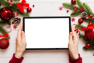 Evden Noel alışverişi, kadın elleri boş beyaz ekranlı tableti tutuyor. Kadın elinde tablet, boş ekran, Noel ağacı ve arka planda hediyeler..