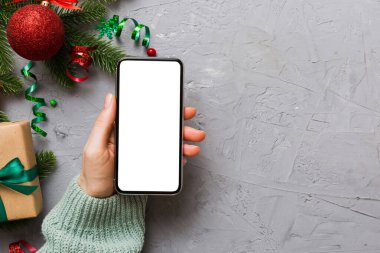 Mesaj atmak için yeri olan bir Noel modeli. Noel reklamı, uygulama şablonu. Masa arkasında boş ekran olan el ele tutuşan telefon. Mutlu yıllar ve Xmas Flat.